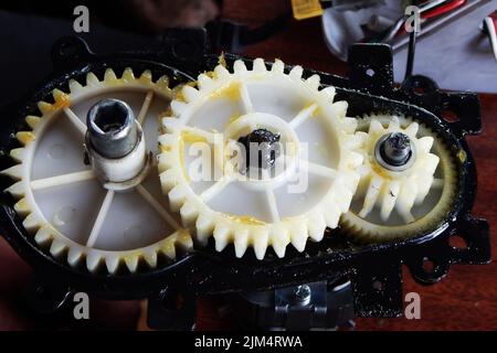 Plastic white gears of the mechanism in yellow grease. High quality photo Stock Photo