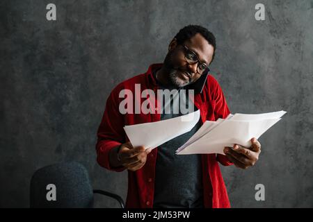 Black man talking on cellphone while working with papers indoors Stock Photo