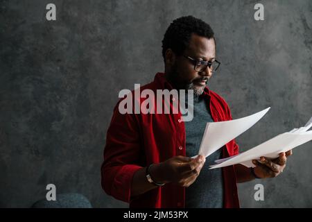 Black bearded man in eyeglasses working with papers indoors Stock Photo