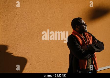 Black bearded man in sunglasses standing by wall outdoors Stock Photo