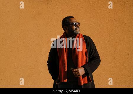 Black bearded man in sunglasses standing by wall outdoors Stock Photo