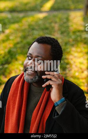 Black bearded man talking on cellphone while strolling at park Stock Photo