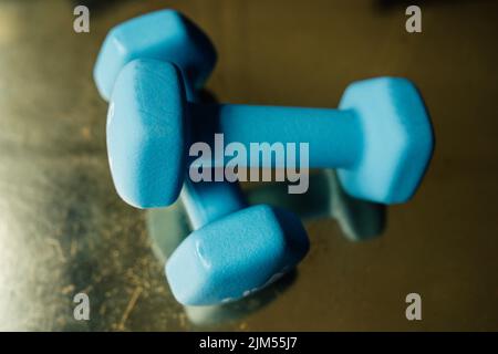two five pound light blue hand weights on reflective golden surface Stock Photo