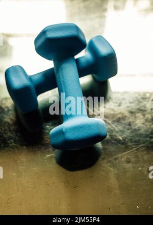 two five pound light blue hand weights on reflective golden surface Stock Photo