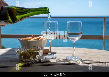 Pouring of txakoli or chacolí slightly sparkling very dry white wine produced in Spanish Basque Country, served outdoor with view on Bay of Biscay, At Stock Photo