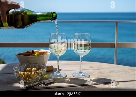 Pouring of txakoli or chacolí slightly sparkling very dry white wine produced in Spanish Basque Country, served outdoor with view on Bay of Biscay, At Stock Photo