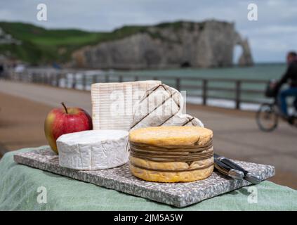 Four famous cheeses of Normandy, squared pont l'eveque, round camembert cow cheese, yellow livarot, heartshaped neufchatel and view on promenade and a Stock Photo