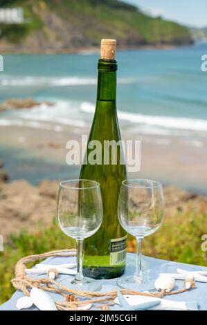 Tasting of txakoli or chacolí slightly sparkling very dry white wine produced in Spanish Basque Country, served outdoor with view on Bay of Biscay, At Stock Photo