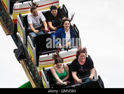 Cranger Kirmes, Herne, NRW, Germany, 04th Aug 2022. Passengers have fun on the 'Alpinabahn' rollercoaster. Visitors enjoy the many attractions, roller coasters, beer halls, carousels and more at the Cranger Kirmes fun fair soft opening ahead of the official opening ceremony tomorrow. This is the first time it takes place since Covid restrictions took hold in 2020. The third largest fun-fair in Germany, and largest in Germany's most populous state NRW, usually attracts 4m  visitors over 10 days. It has a long tradition with fairs having taken place on the site since the early 18th century. Stock Photo