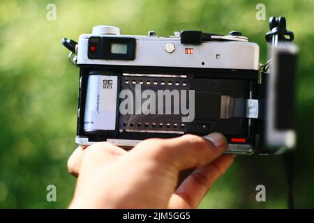 Hand holding rear view analog camera with negative film on in Stock Photo