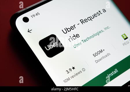 Uber app seen in Google Play Store on the smartphone screen placed on red background. Close up photo with selective focus. Stafford, United Kingdom, A Stock Photo