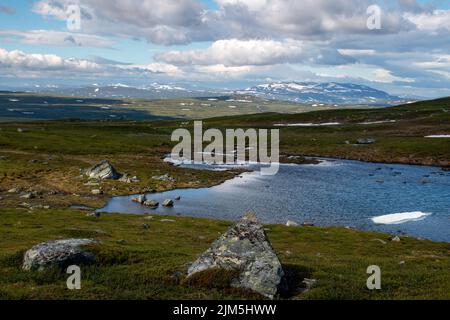 A lake of melting ice along the hiking trail between Blahammaren mountain station in Sweden and Storerikvollen mountain station in Norway. Stock Photo