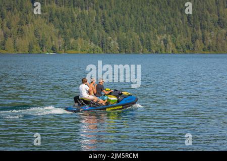 Father with his sons having fun jumping a wave riding jet ski on a Cultus Lake British Columbia, Canada. Summer vacation activity, water sports concep Stock Photo