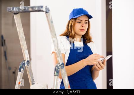 Female construction worker using smartphone in apartment Stock Photo