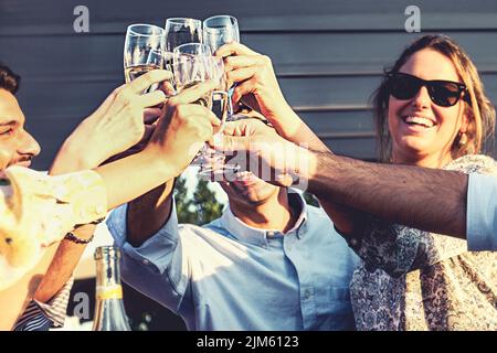 Cheerful young friends having a celebratory toast in the resort backyard - happy people clinking champagne flute glasses - people and alcohol lifestyl Stock Photo
