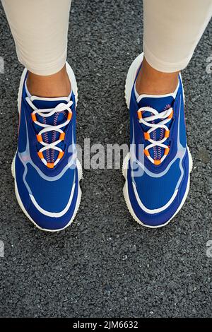Woman's legs in blue sneakers outdoor, close up. Modern sport fashion concept. Stock Photo