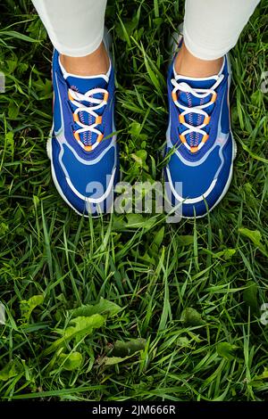 Woman's legs in blue sneakers outdoor, close up. Modern sport fashion concept. Stock Photo