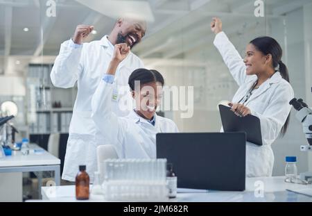 Celebrating another case solved. a group of scientists cheering while working in a lab. Stock Photo
