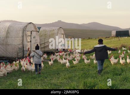 Less tv, more childhood memories. Rearview shot of two adorable children playing on a chicken farm. Stock Photo