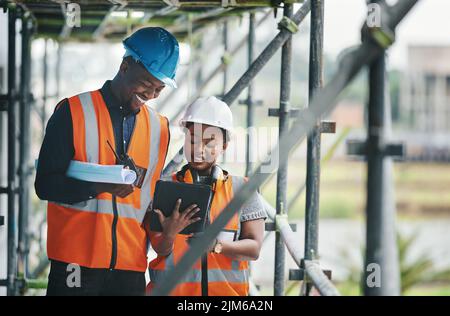Collecting, storing and tracking all building compliance documentation. a young man and woman using a digital tablet while working at a construction Stock Photo