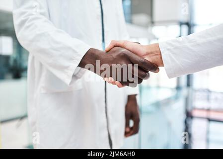 Improving clinical performance through teamwork. Closeup shot of two doctors shaking hands in a hospital. Stock Photo