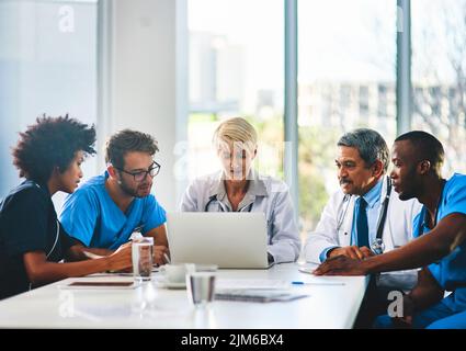 Team of doctors in a meeting planning and brainstorming in a boardroom using a laptop to read notes. Group of healthcare professionals discussing and Stock Photo
