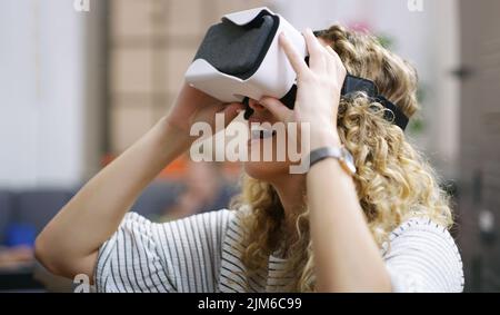 Wow It seems so real. a young businesswoman using a virtual reality headset in a modern office. Stock Photo