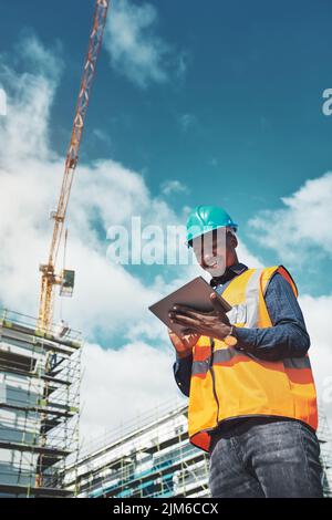 The smartest project management solution. a young man using a digital tablet while working at a construction site. Stock Photo