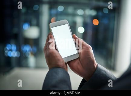 Businessman hands holding phone with white screen template in modern office. Closeup businessperson reading text message on smartphone at night while Stock Photo