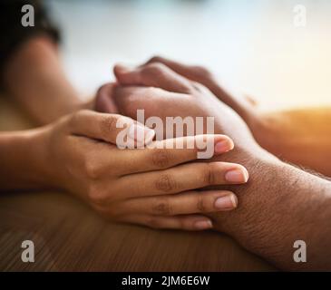 Holding hands showing care, love and support between friends, couple or family. People comforting, giving affection and consoling with a hand gesture Stock Photo