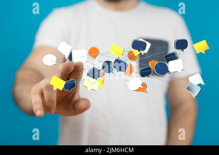 A businessman tapping on a digital render of a network of colorful speech bubble icons Stock Photo