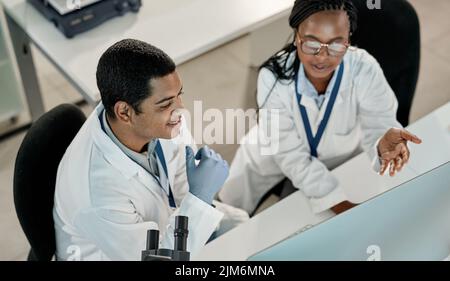 Working on something new. two scientists working together on a computer in a lab. Stock Photo