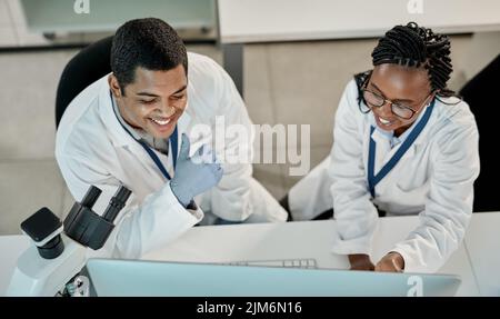 Getting things done in the lab. two scientists working together on a computer in a lab. Stock Photo