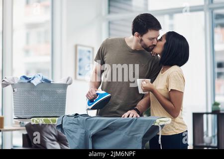 A marriage made in heaven. an affectionate young couple ironing freshly washed laundry together at home. Stock Photo