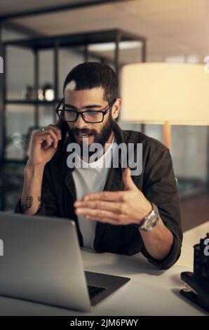 Successful people dont stray from the slay. a young businessman using a smartphone and laptop during a late night at work. Stock Photo