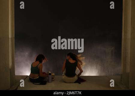 Washington, DC, 04 Aug 2022, Two women try to eat while sitting on a ledge at the Lincoln Memorial during a heavy thunderstorm. The afternoon high temperature in Washington was 94°F (34.4°C). Credit: Philip Yabut/Alamy Live News Stock Photo
