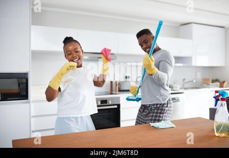 Divide and conquer. a happy young couple having fun while cleaning the kitchen at home. Stock Photo