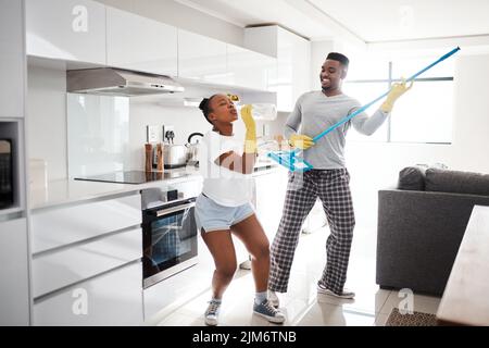 Nothing makes a marriage sparkle like good, clean fun. a happy young couple having fun while cleaning the kitchen at home. Stock Photo