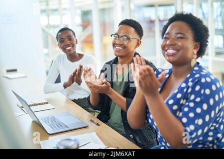 The most productive meetings leave everyone feeling motivated. a group of businesspeople clapping during a meeting in a modern office. Stock Photo