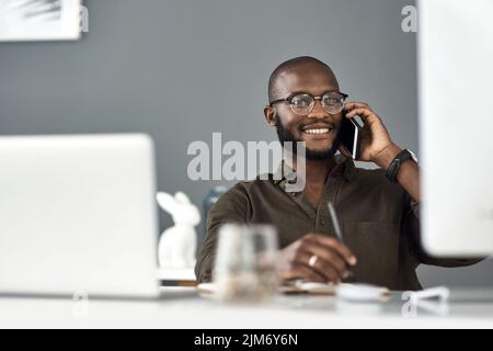 One call gets it all. a young businessman using a smartphone and computer in a modern office. Stock Photo