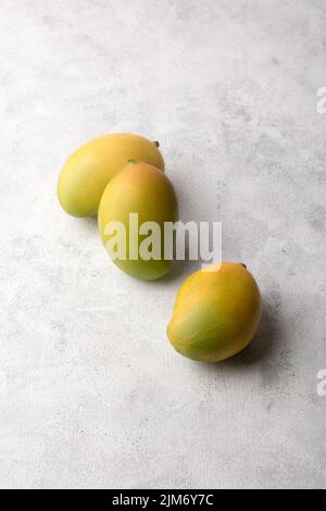 mangoes, tropical fruit on white textured surface background, copy space Stock Photo