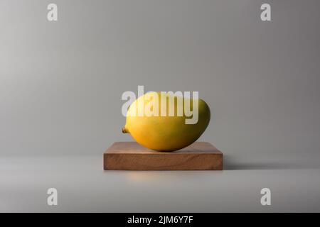 ripe mango, tropical fruit on wooden tray, neutral gray background Stock Photo