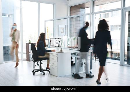 Coworking must go on. a group of businesspeople wearing face masks while working in an office. Stock Photo