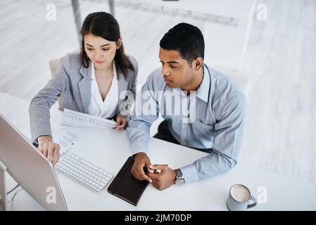 A collaborative work culture keeps quality up. a young businessman and businesswoman using a computer in a modern office. Stock Photo