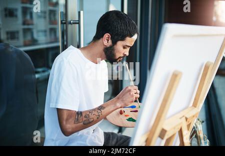 Open your mind to artistic possibilities. a man doing a painting while sitting on the balcony at home. Stock Photo