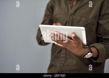 Do it the quicker way with digital tech. Studio shot of an unrecognisable businessman using a digital tablet against a gray background. Stock Photo
