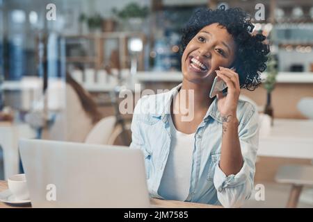 It feels good when your hard work starts to pay off. a businesswoman talking on her cellphone while working from a cafe. Stock Photo