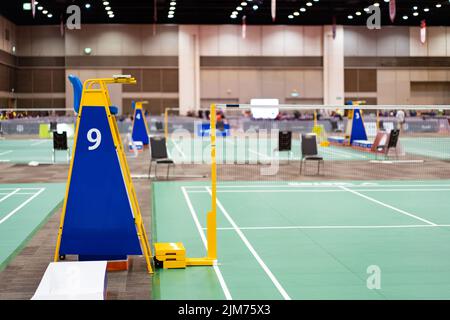 Blue chair of badminton referee with yellow colors near badminton net with blurred background in sport indoor stadium. Stock Photo