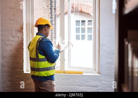 Doing it right costs less than doing it over. a engineer making notes while on a construction site. Stock Photo
