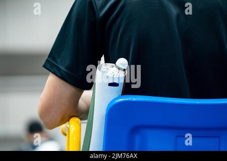 Blue chair of badminton referee with yellow colors near badminton net with blurred background in sport indoor stadium. Stock Photo